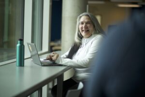 Indigenous student from the Fort McKay First Nation smiling at the camera while studying in a campus common space.