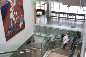 Two Indigenous students from the Metis and Fort McKay First Nations talking while walking down the stairs in a campus common space.