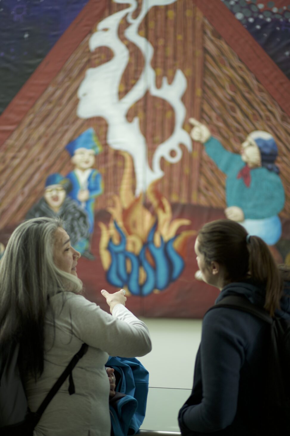 Two indigenous students talking about the piece of art that is in front of them. Students from the Metis and Fort McKay First Nations.