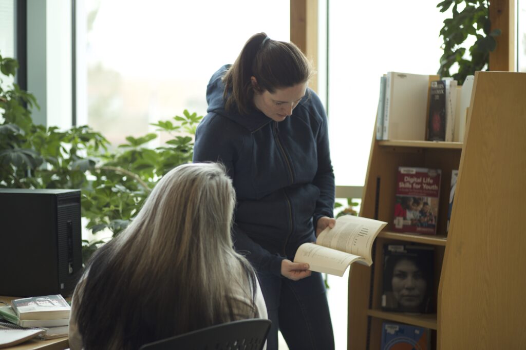 Two Indigenous students from the Metis and Fort McKay First Nations reading a book at a campus library.