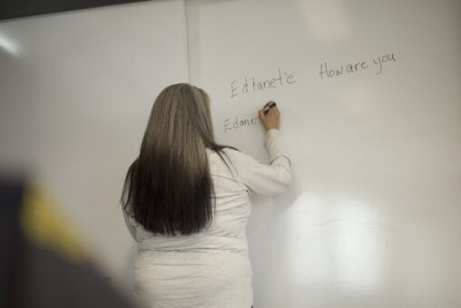 Indigenous teacher from the Fort McKay First Nation teaching Indigenous language by writing on a whiteboard.