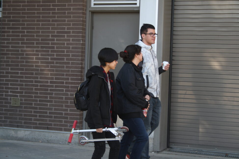 Three Indigenous students from the Haida and Ntekepmx Nations walking outdoors on campus.