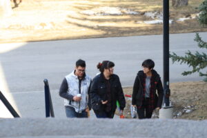 Three Indigenous students climbing up outdoor stairs on campus.