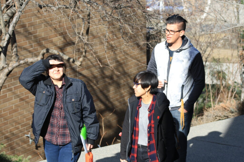 Three Indigenous students from the Haida and Ntekepmx Nations walking outdoors on campus.