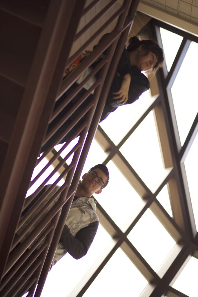 Indigenous students from the Haida and Ntekepmx Nations looking down from the next set of stairs inside of a building on campus.