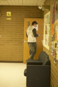 Indigenous student from the Haida Nation walking into a classroom in a campus building.