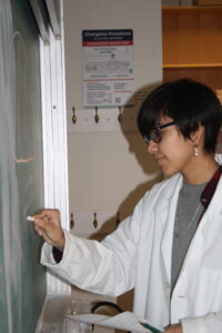 Indigenous student from the Ntekepmx Nation writing on a chalkboard in a science laboratory.