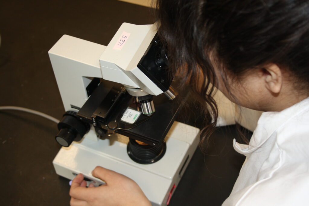 Indigenous student from the Ntekepmx Nation using a microscope in a biology laboratory.