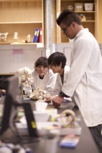 Three Indigenous students from the Haida and Ntekepmx Nations, studying a human skull in an anatomy laboratory.