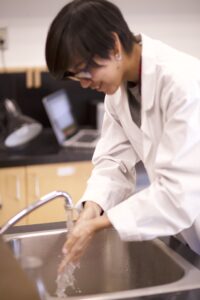 Indigenous student from the Ntekepmx Nation washing their hands in a science laboratory.