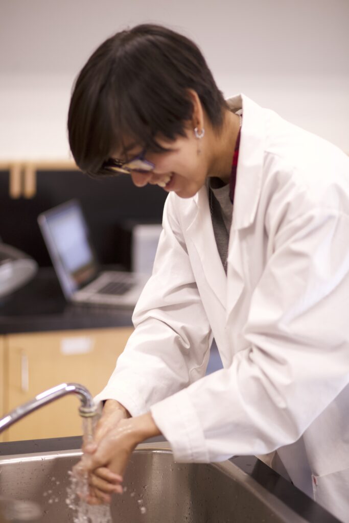 Indigenous student from the Ntekepmx Nation washing their hands in a biology laboratory.