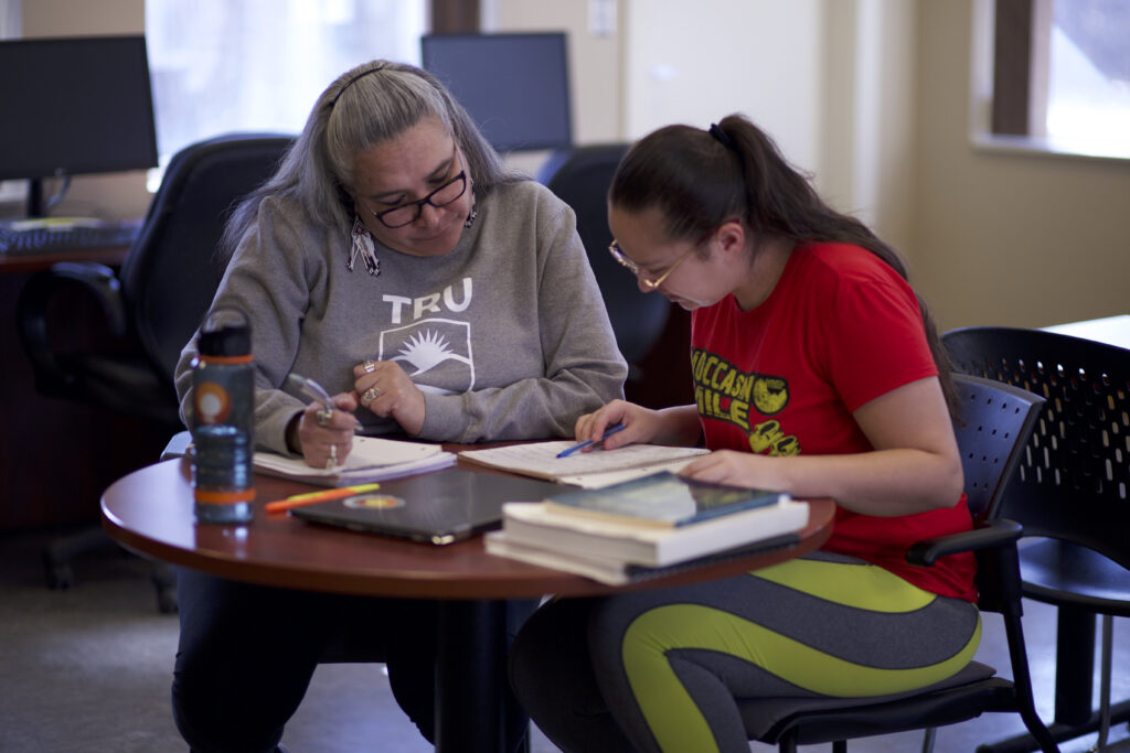 Two indigenous students from the Stat'imc/Nlakapamux Fort McKay First Nations studying while reviewing their notes at a common space on campus.