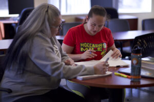 Two Indigenous students from the St'at'imc/Nlaka'pamux and Fort McKay First Nations studying using their notebooks at a campus common space.