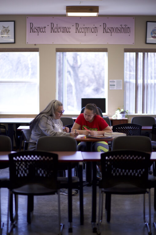 Two Indigenous students from the St'at'imc/Nlaka'pamux and Fort McKay First Nations studying using their notebook notes in a campus common space.