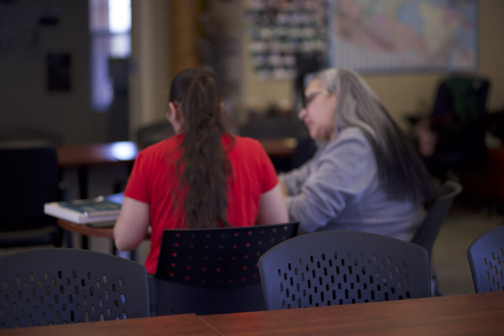 Two indigenous students from the St'at'imc/Nlaka'pamux and Fort McKay First Nations sitting down on a table and studying at a common space on campus.