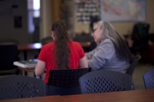 Two indigenous students from the St'at'imc/Nlaka'pamux and Fort McKay First Nations sitting down on a table and studying at a common space on campus.