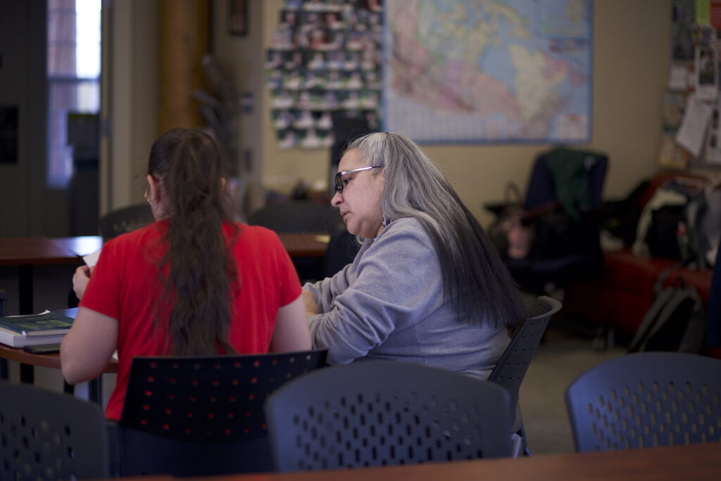 Two Indigenous students from the St'at'imc/Nlaka'pamux and Fort McKay First Nations studying at a table in a campus common space.