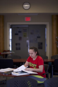 Indigenous student from the Stat'imc/Nlakapamux Nation making some notes and studying at a common space on campus.