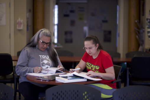 Two indigenous students from the St'at'imc/Nlaka'pamux and Fort McKay First Nations studying from their books and notes at a common space on campus.