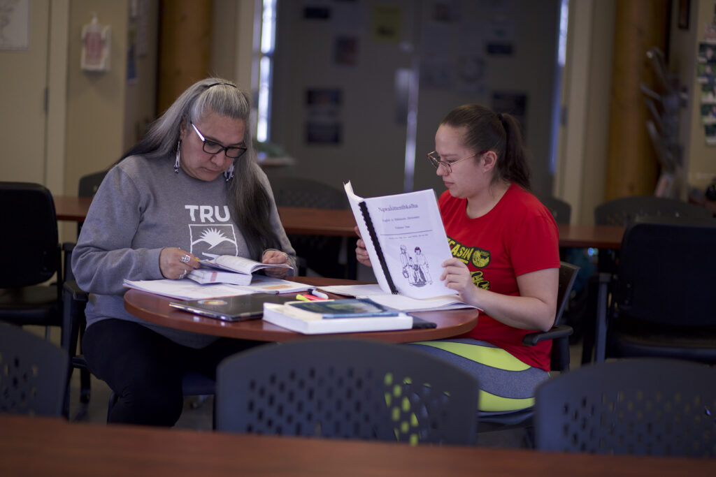 Two indigenous students from St'at'imc/Nlaka'pamux and Fort Mckay First Nations, reading some books at a common space on campus.