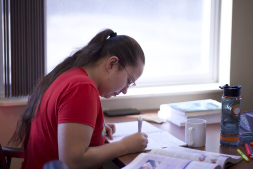 Indigenous student from the Stat'imc/Nlakapamux Nation making some notes and studying at a common space on campus.