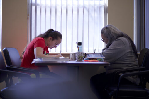 Two indigenous students from the St'at'imc/Nlaka'pamux and Fort McKay First Nations studying and taking notes at a common space on campus.