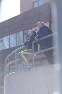 Two indigenous students from the Stat'imc/Nlaka'pamux and Fort McKay First Nations talking outdoors in front of a campus building.